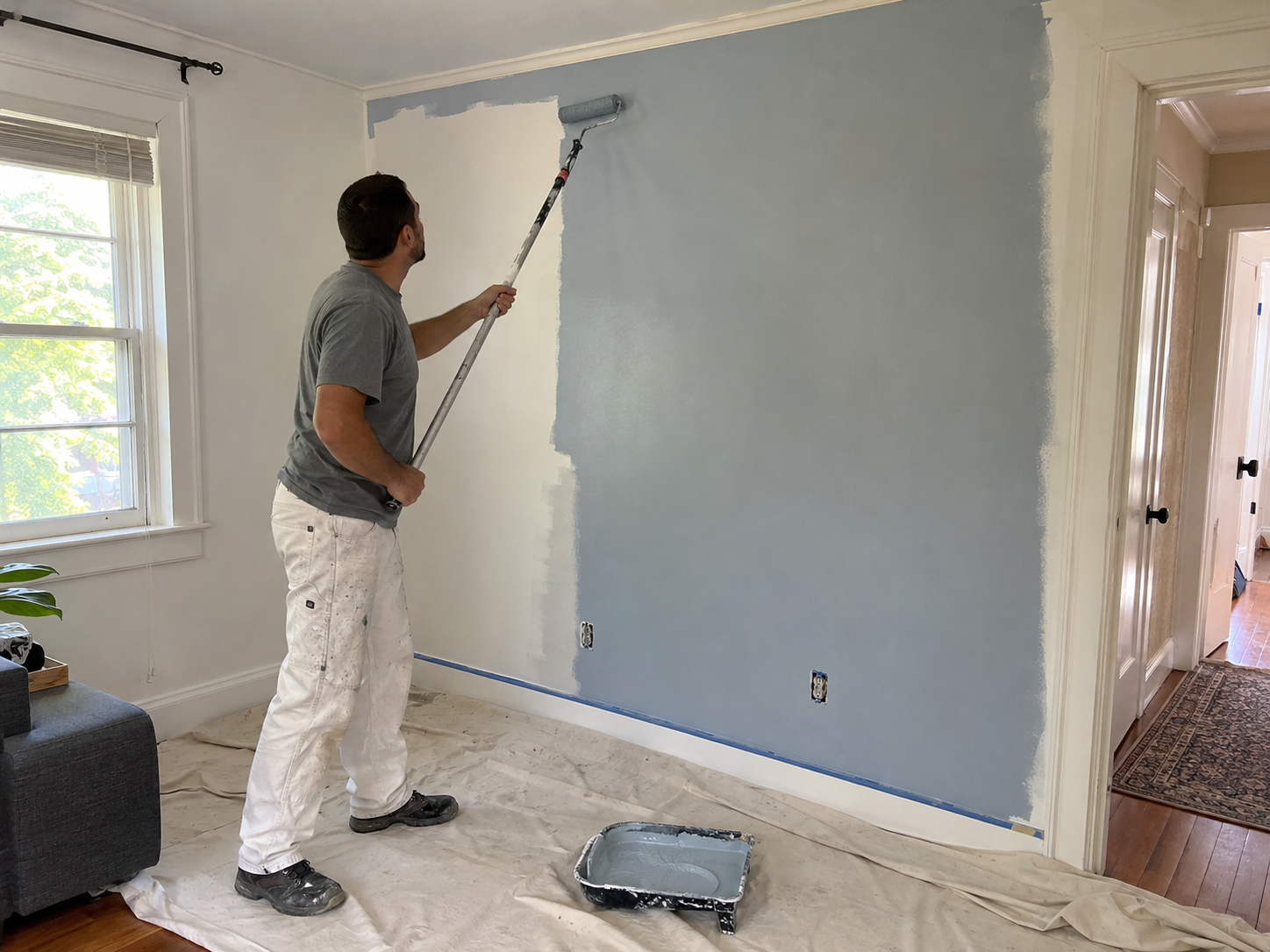 Painter rolling light blue paint on an interior wall