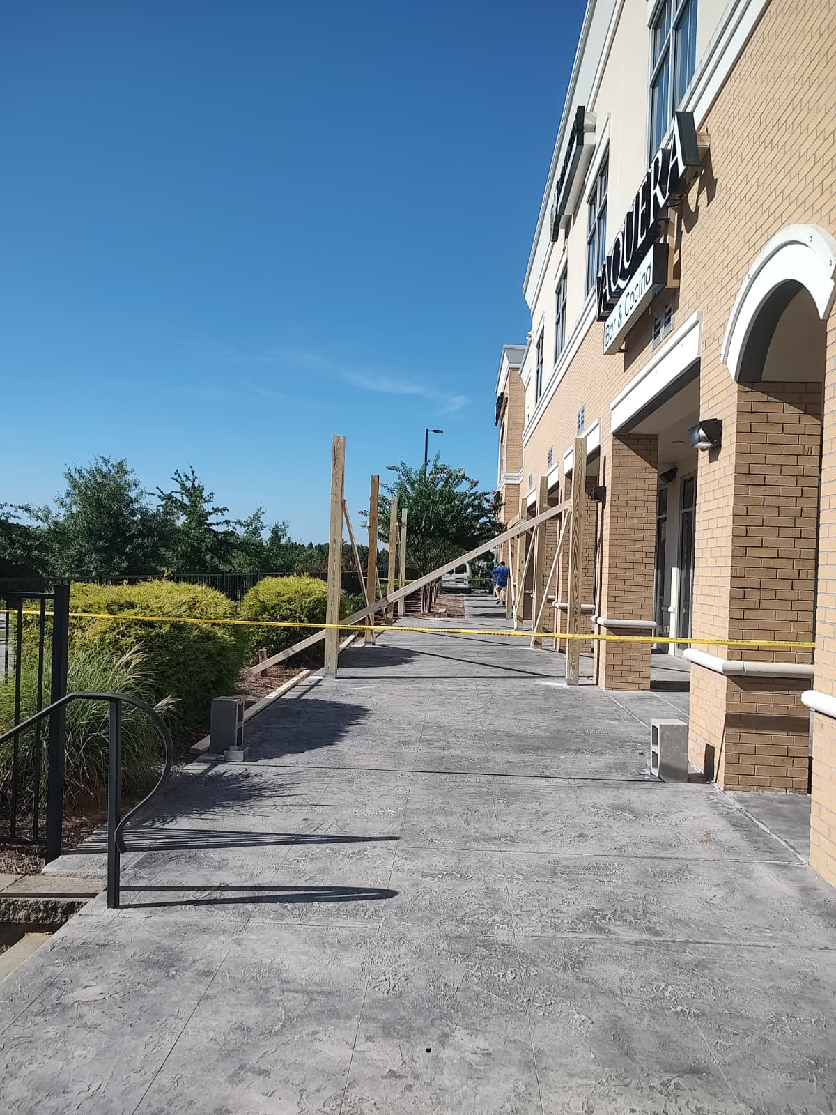 Concrete walkway alongside a brick building before the pergola was built